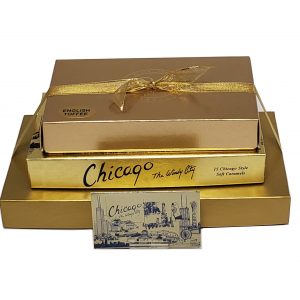 Three gold gift boxes are stacked, with a gold ribbon on the top box. The middle box is labeled “Chicago The Windy City,” and a vintage-style Chicago postcard is in front.
